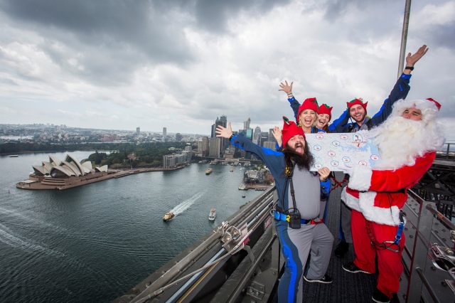 People dressed as Santa Claus and his elves stand on top of the Sydney Harbour Bridge